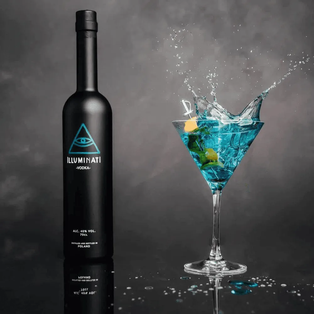 A blue cocktail splashing in a martini glass beside an Illuminati Vodka bottle